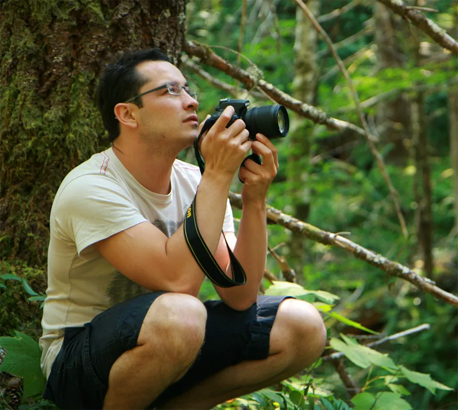 David  croutched down, holding and camera and looking up
